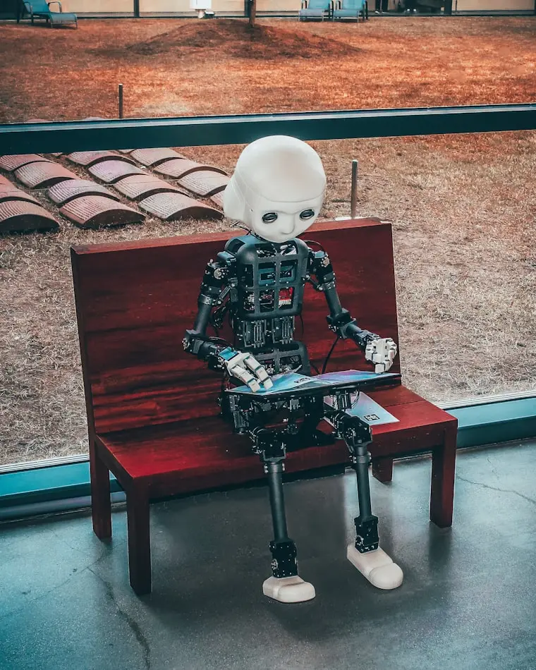 A humanoid robot sitting on a wooden bench reading a book, representing AI search models, Generative Engine Optimization, and AEO marketing strategies.